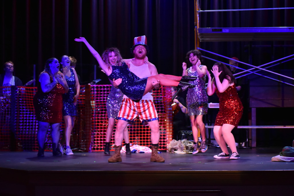 Paul Keays (center) as Favorite Son holding Elizabeth Vinson with the company of American Idiot 📸 Mort Shuman