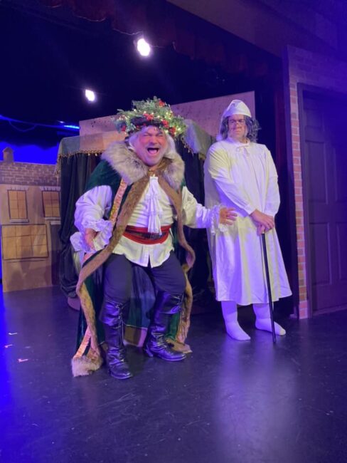 B. Tommy Rinaldi (left) as Ghost of Christmas Present with Bobby Mahoney (right) as Scrooge in A Christmas Carol at Tidewater Players 📷 Sarah O'Hara